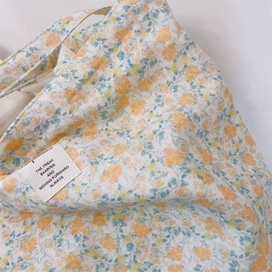 Macro detail of floral canvas tote bag featuring premium fabric texture and woven label
