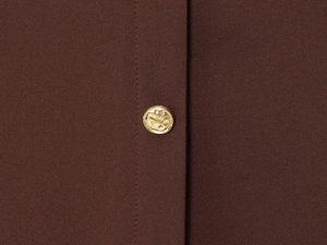 Detail of dark coffee crepe fabric and hammered gold metal button on midi dress