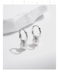 Close-up of S925 sterling silver hallmark and white pearl on irregular hoop earrings