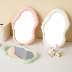 Close-up of wavy irregular vanity mirrors in pastel pink, cream white, and light green shades
