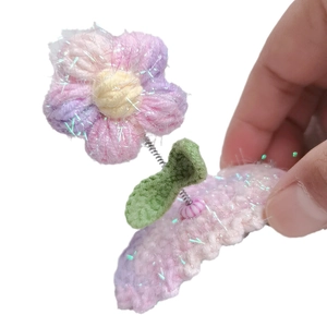 Pink hand-crocheted puff flower hair clip with shimmer yarn and green leaf detail