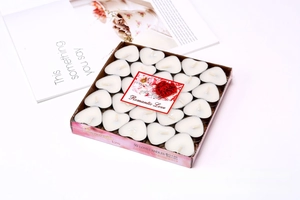 Macro detail of 50 heart-shaped white tea light candles in romantic gift packaging