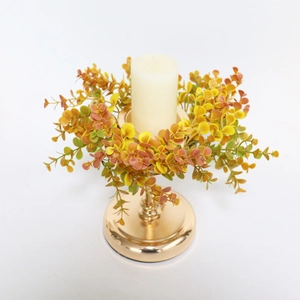 Macro detail of orange eucalyptus wreath with golden metal candle holder and pillar candle