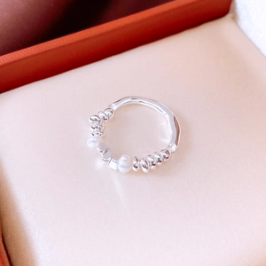 Close-up of minimalist silver beaded ring with white pearls on golden satin