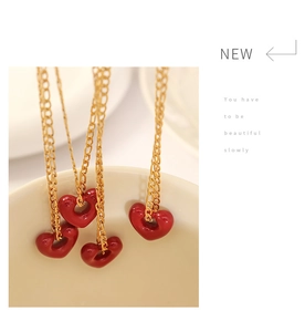 Close-up of red heart pendant necklaces on a white ceramic bowl with gold chains