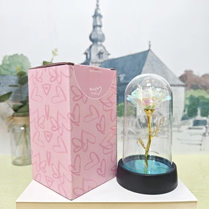 Detail of colorful gold foil rose in a glass dome with a pink heart pattern gift box