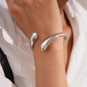 Polished silver irregular drop-end open cuff bracelet shown on female wrist
