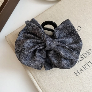 Detail of grey fabric bow hair claw clip with black pattern on a vintage book