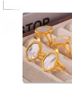 Detailed macro of irregular 18k gold plated rings with white shell inlays on velvet tray