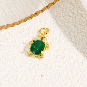 Macro view of gold turtle pendant with green oval gemstone and top link ring
