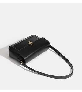 Detailed view of black smooth leather underarm bag with gold ring buckle hardware