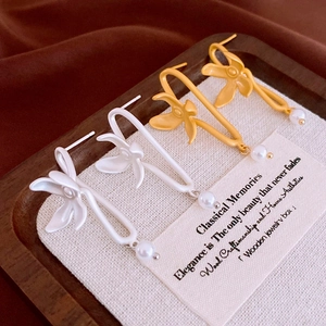 Minimalist matte flower earrings with pearls on a wooden tray with silk background