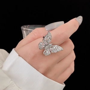 Gros plan détaillé d'une bague papillon en argent sertie de zircons sur un doigt