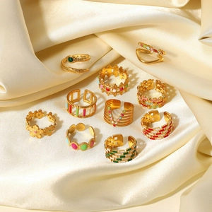 Collection of 10 gold plated stainless steel rings with enamel details on white silk