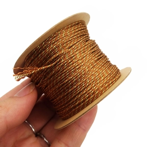 Detailed macro of 1mm gold and brown twisted metallic thread on a circular spool