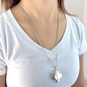 Polished silver cross pendant necklace shown on model with sleek curb chain detail