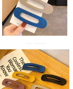 Macro shot of large matte oval hair clips in assorted Morandi colors on wooden desk