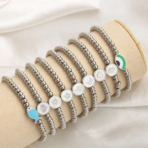 Stack of 4mm stainless steel beaded bracelets with diverse charms on a velvet display