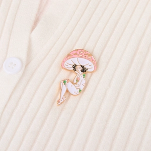 Creative mushroom person enamel pin in pink and white on a beige cardigan
