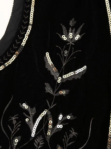 Detailed macro view of black velvet fabric with intricate sequin floral embroidery