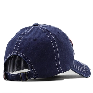 Détail de la casquette en jean bleu avec coutures contrastées et bordure effet usé