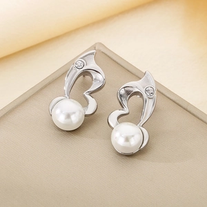 Detail of silver musical note earrings with white pearls and diamonds on silk background