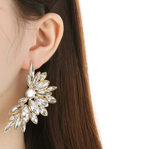 Close-up of vintage gold leaf earrings with crystals worn by a model for a luxury look