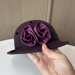 Detail of wool felt hat with satin roses and polka dot mesh veil in dark purple