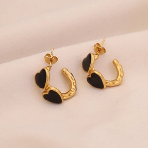Detailed view of C-shaped gold heart earrings with black enamel finish on velvet base