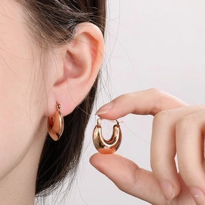 Detailed view of chunky rose gold U-shaped hoop earrings with polished metallic finish
