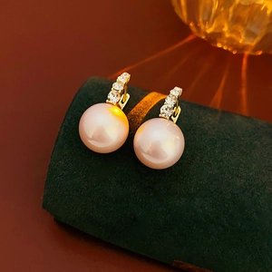 Macro detail of pink pearl drop earrings with sparkling zircon inlay on green velvet