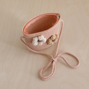 Detail of pink straw crossbody bag with crochet flowers and secure zipper closure