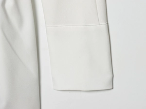 Detail of white batwing sleeve dress showing premium woven texture and fine stitching