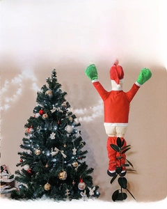 Detail of creative climbing Santa Claus plush decoration hanging on a Christmas tree