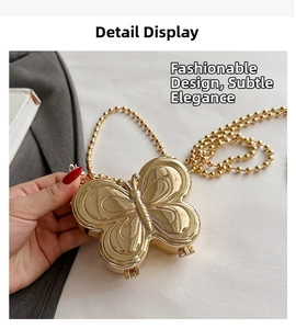 Detail view of mini gold butterfly metal box bag with polished mirror finish and chain