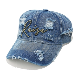 Detail of washed denim baseball cap with Raisa embroidery, distressing and metal rings