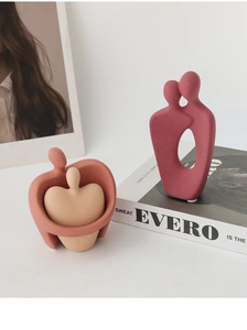 Detailed macro view of matte textured Morandi ceramic abstract couple sculptures on book
