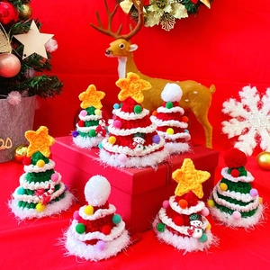 Detailed view of hand-knit Christmas tree and star hats for pets in festive red and green