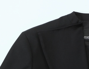 Gros plan du revers de veste de costume noir montrant le tissu texturé et les coutures