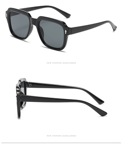 Detail view of square oversized sunglasses with glossy black frames and gray lenses