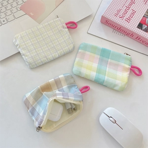 Detail of grid fabric pouch showing interior storage for AirPods and a USB charging cable
