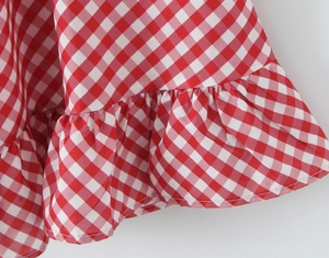 Gros plan sur un tissu à carreaux rouge et blanc avec ourlet à volants et fronces