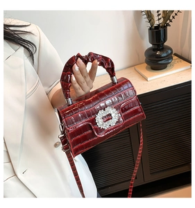 Détail du sac rouge effet crocodile avec boucle en cristal et poignée plissée élégante