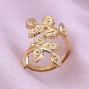 Detailed macro of golden olive leaf ring on purple silk background with wrap design