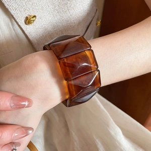 Close-up of amber tortoiseshell acrylic bangle with geometric faceted segments on wrist