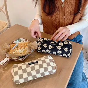 Vintage corduroy pencil case with floral and checkered patterns on a wooden table