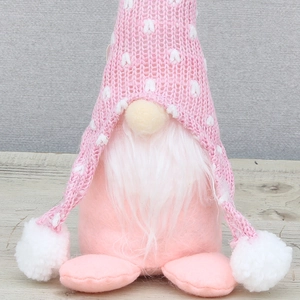 Détails d'un gnome rose tricoté avec barbe blanche et bonnet à motifs de cœurs