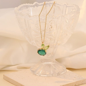 Golden rabbit pendant necklace with green gemstones on crystal glass display