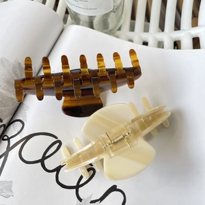 Large acetate hair claws in amber and cream white set on book pages for a French look