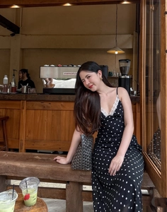 Vue détaillée d'une robe nuisette à pois noire avec dentelle et sac à main dans un café